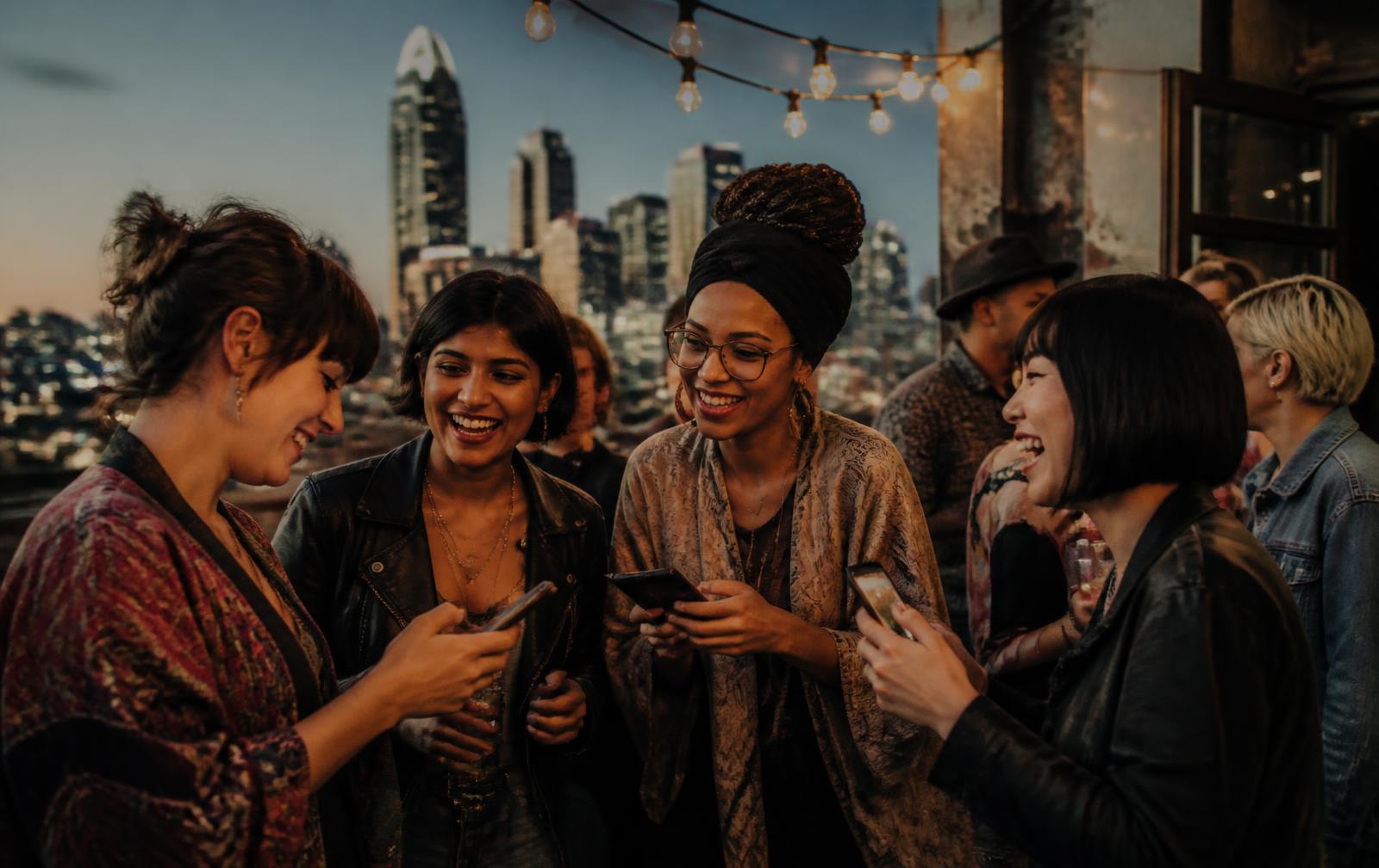 A diverse group of people connecting at a rooftop gathering at dusk